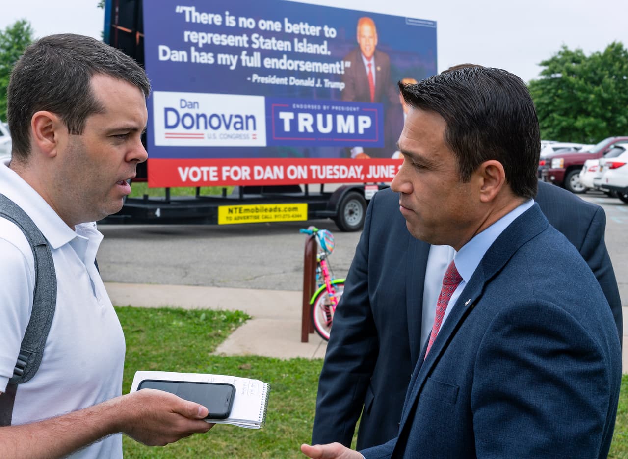 Former Rep. Michael Grimm right, speaks to reporter as he attends a property tax protest rally in the Staten Island borough of New York, Sat. June 23, 2018. Grimm is opposing Dan Donovan, R-N.Y., seen on a campaign sign in background, for the Republican Congressional primary for the 11th Congressional District. (AP Photo/Craig Ruttle)