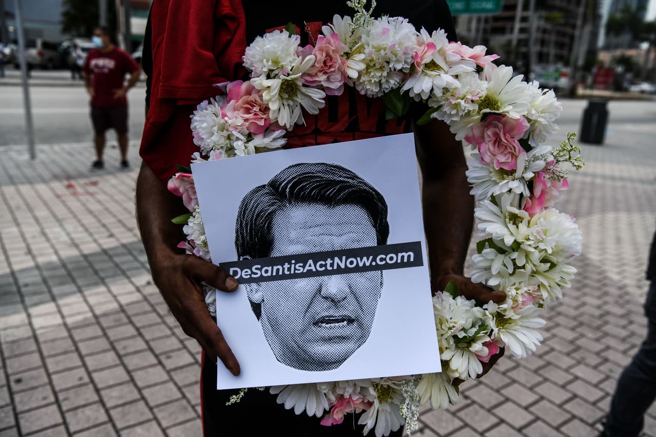 Manifestantes critican la labor del gobernador de Florida, Ron DeSantis, al omitir el uso del tapabocas como obligatorio ante el aumento de muertes y contagios de covid-19 en el estado.