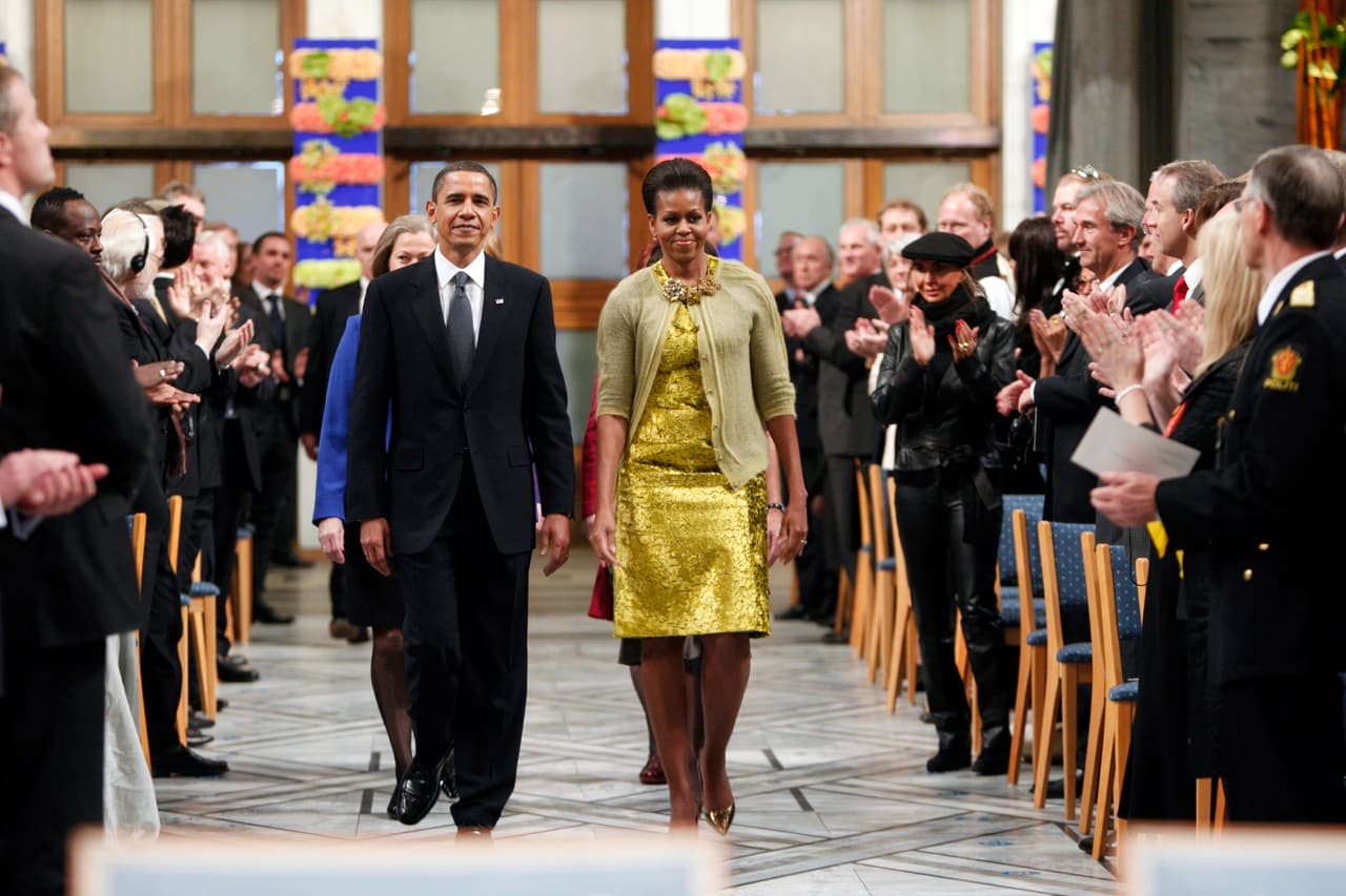Para asistir a la ceremonia del Premio Nobel de la Paz de 2009, Michelle Obama también consideró que su vestido amarillo con visos dorados emparentaba perfecto con un cárdigan mostaza abotonado solo en el primer botón, con un prominente collar.