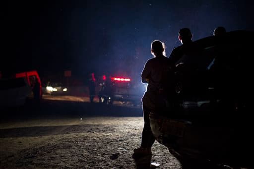 Los residentes evacuados de sus casas se sitúan en un control de carretera de la policía.