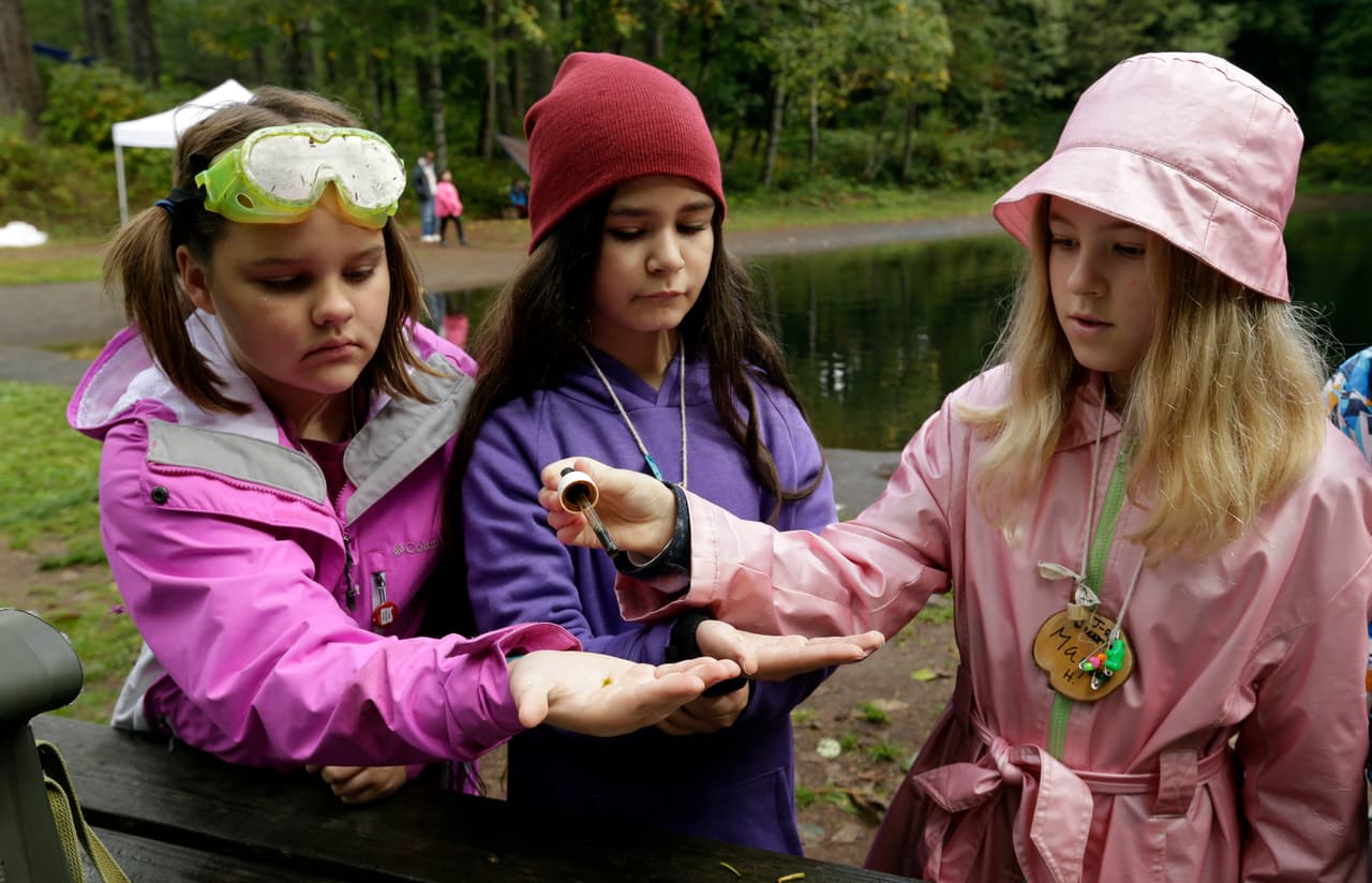 In this Oct. 6, 2016, photo, from left, Outdoor School students Evie Larson, Lillyann Samson and Maya Herring run a test on pond water during a lesson at Camp Howard in Mount Hood National Forest near Corbett, Ore. The outdoor education is unique to Oregon and is a rite-of-passage for public school students that's meant to instill a respect for nature in each generation - studies show it improves attendance and boosts test scores. (AP Photo/Don Ryan)