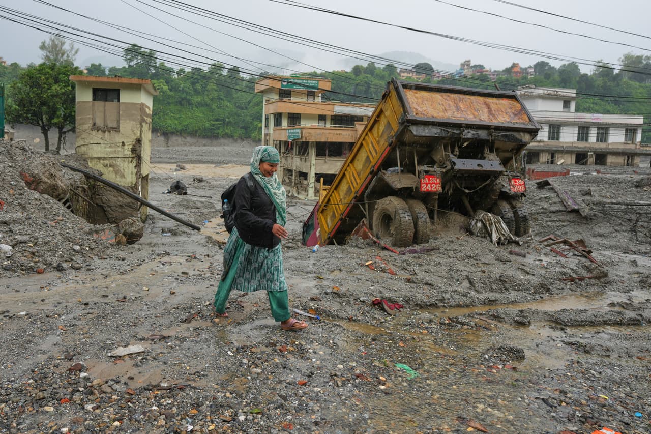 Una mujer camina entre el barro y los escombros dejados por una inundación repentina, el sábado 29 de agosto de 2026, en el distrito de Nuwakot, Nepal.