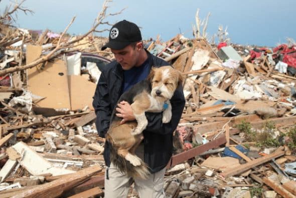 Sean Xuereb abraza a un perrito perdido entre los escombros. Muchas mascotas se encuentran desubicadas tras el tornado, a la espera de que sus dueños las encuentren.