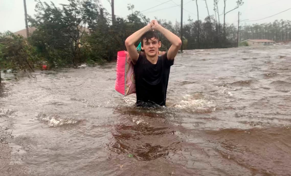 Al menos cinco personas fallecieron en el archipiélago después de varias horas de fuertes vientos y copiosa lluvia. En la fotografía un joven con el agua hasta la cintura mientras es rescatado en una calle inundada de Freeport, en la isla Gran Bahama.