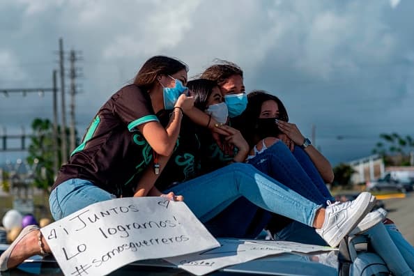"¡Juntos lo logramos! #SomosGuerreros" dice el cartel de una de estas graduandas.