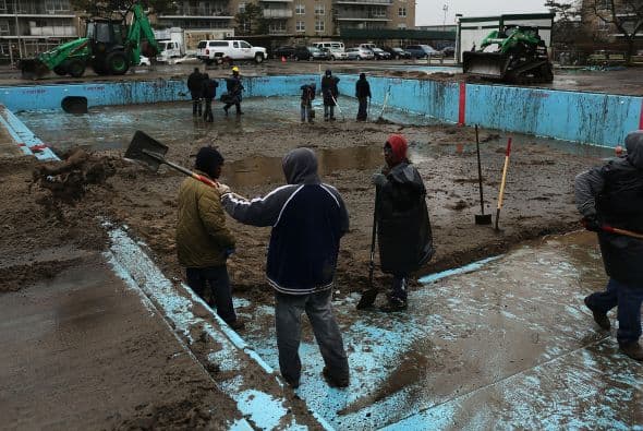 En esta imagen, trabajadores limpian una alberca que se econtraba cubierta de arena en Rockaway, Queens.