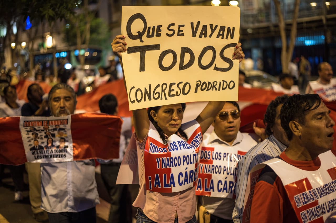 A woman holds up a sign reading "Throw them all out. Rotten Congress" during a protest against political corruption in Lima on March 22, 2018. Peruvian President Pedro Pablo Kuzcynski resigned on March 21, 2018 under political pressure and criticism after he was accused of profiting on business deals made while he held a public office. Congressmen will vote on whether to accept the resignation and proceed with the constitutional procedure of swearing the first vice-President Martin Vizcarra, currently acting as Perus ambassador to Canada or impeach Kuczynski on moral misconduct. / AFP PHOTO / Ernesto BENAVIDES (Photo credit should read ERNESTO BENAVIDES/AFP/Getty Images)