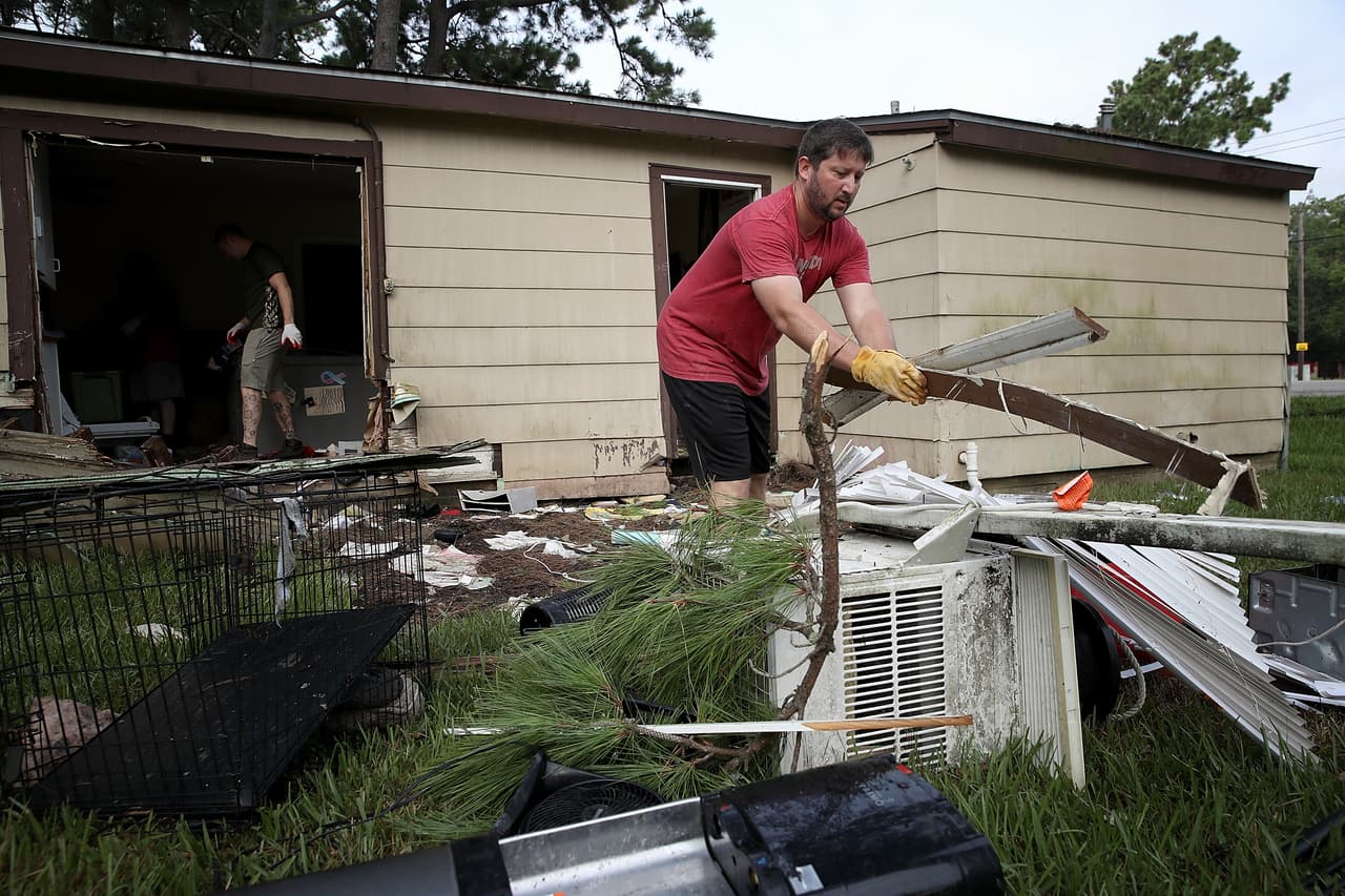 Chris Gaspard ayuda a su amigo Bryan Parson a sacar de su casa los objetos arruinados por el agua, en Dickinson, Texas.