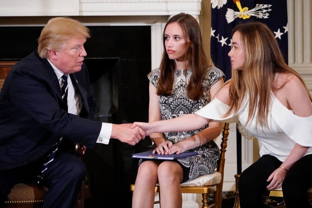 US President Donald Trump shakes hands with Marjory Stoneman Douglas High School student Ariana Klein (R) watched by fellow student Carson Abt at the start of a listening session on gun violence with teachers and students in the State Dining Room of the White House on February 21, 2018. / AFP PHOTO / MANDEL NGAN (Photo credit should read MANDEL NGAN/AFP/Getty Images)