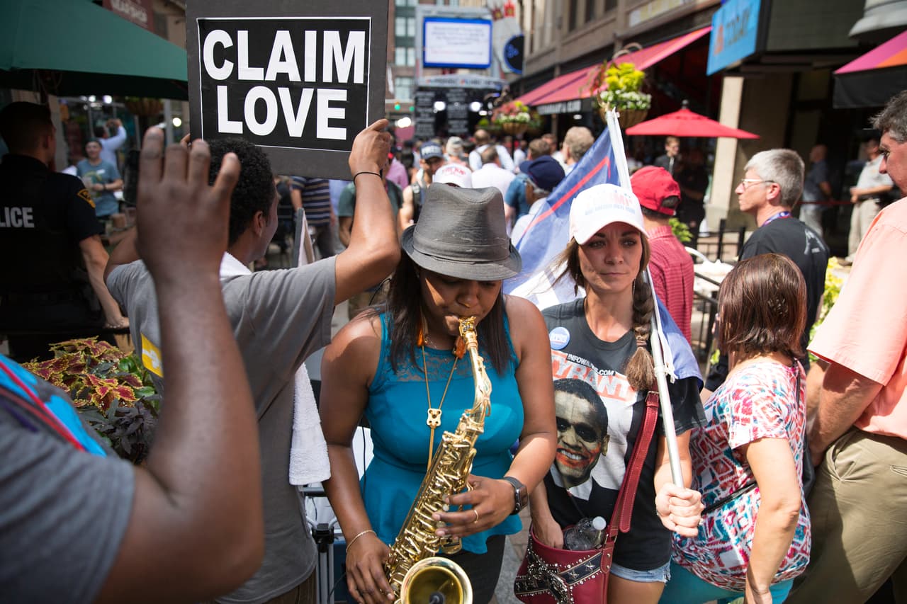 Algunos manifiestan individualmente en una concurrida calle por donde pasan los delegados republicanos que van a pie a la convención.