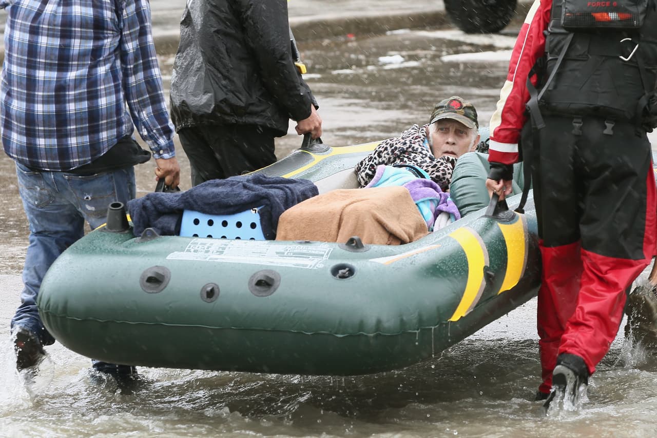 HOUSTON, TX - AUGUST 29: Rescue workers and volunteers help residents make their way out of a flooded neighborhood after it was inundated with rain water following Hurricane Harvey on August 29, 2017 in Houston, Texas. Harvey, which made landfall north of Corpus Christi August 25, has dumped nearly 50 inches of rain in and around areas Houston. (Photo by Scott Olson/Getty Images)