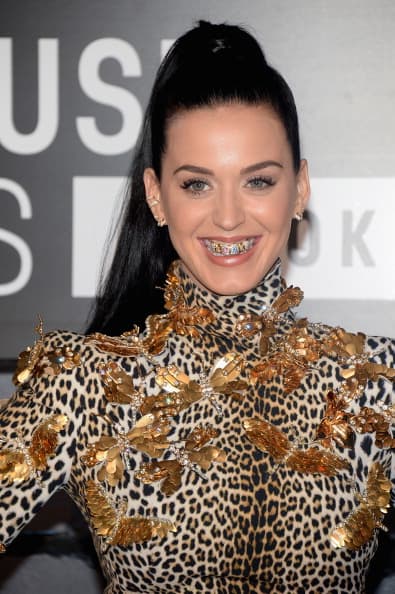 La intérprete de 'Roar', Katty Perry, combinó varios colores con en sus dientes postizos de base en oro para complementar su ajuar durante la alfombra roja de los
<i> MTV Video Music Awards</i> en 2013.