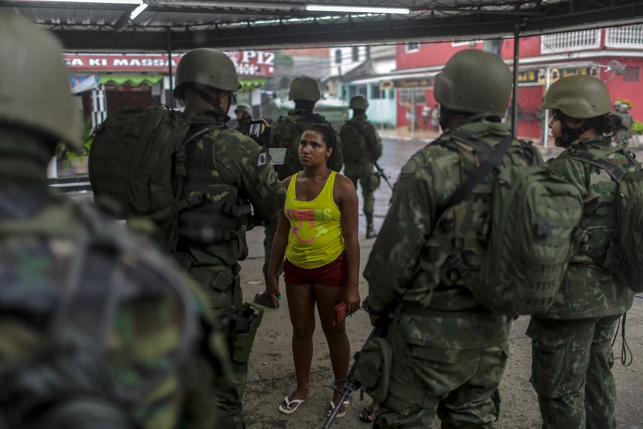 BRA17. RÍO DE JANEIRO (BRASIL), 23/02/2018.- Un miembro de las Fuerzas Armadas toma un foto a una hombre con su documento de identidad durante un operativo de seguridad hoy, 23 de febrero de 2018, en Río de Janeiro (Brasil). Unos 3.200 militares de las Fuerzas Armadas volvieron a salir hoy a las calles de Río de Janeiro en una operación contra el crimen organizado, cuando se cumple una semana desde que el presidente brasileño, Michel Temer, decidiera cederle al Ejército el control de la seguridad de ese estado. EFE/ Antonio Lacerda