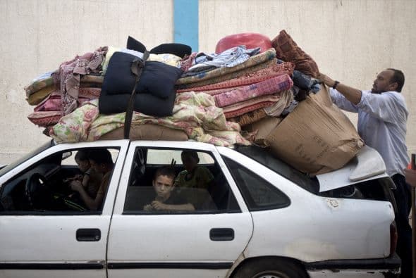 Un gazatí amarra sus pertenencias al techo de su coche ya que él y su familia se preparan para regresar a casa después de permanecer en un refugio de la ONU.