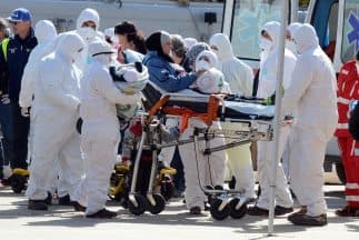 Personal médico lleva en una camilla a una mujer y su pequeño hijo rescatados de una embarcación ilegal que transportaba indocumentados que habían zarpado desde Libia rumbo a Italia.