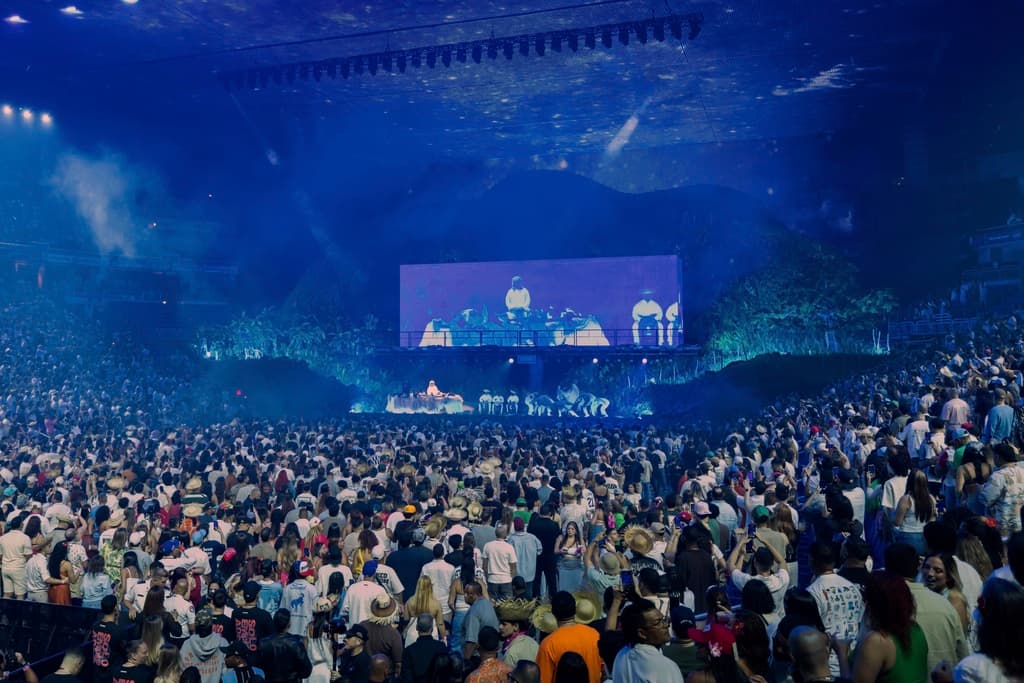 <b>Un escenario que simboliza la gentrificación:</b>
<br>Parte de los conciertos se desarrolla en un segundo escenario montado como una casa tradicional puertorriqueña, desde donde el artista plantea preguntas sobre si ahora pertenece a turistas o es un Airbnb, reflejando la preocupación por el desplazamiento social.