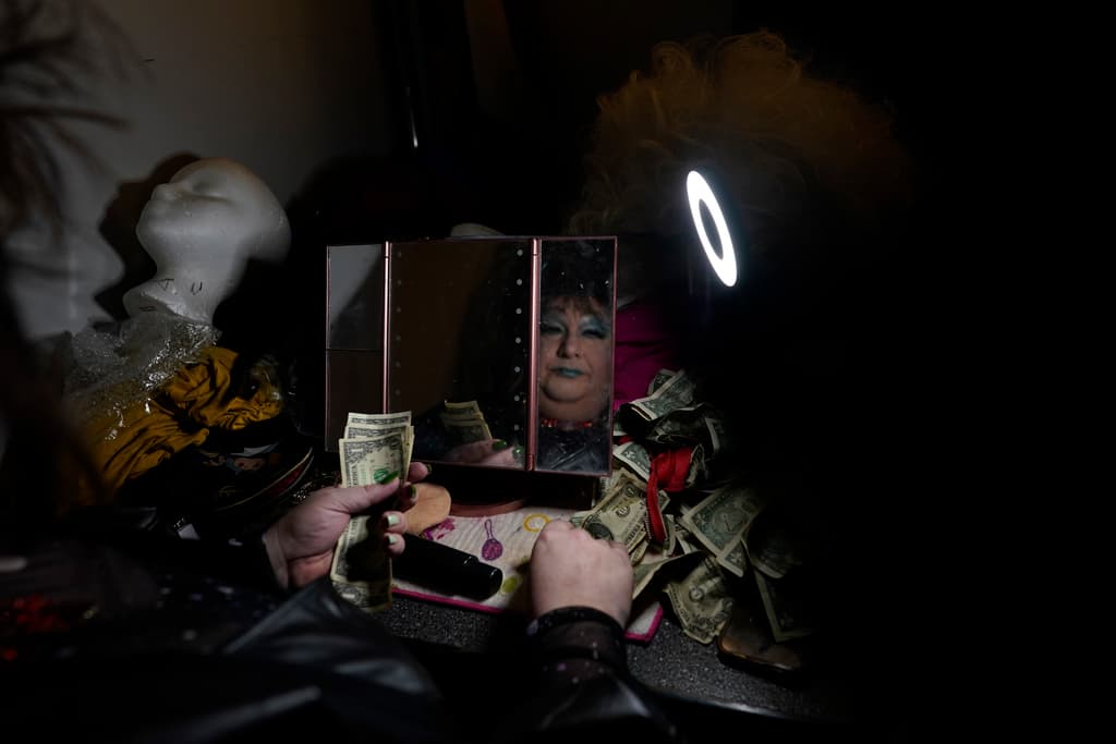 La drag queen Alexus Daniels, vestida como Tina Turner, reflejada en un espejo al contar propinas en el vestidor durante el espectáculo "Spring Fever Drag Brunch" en Kulpmont, Pensilvania. “¡Sabía que me atraían los chicos y amaba todo lo femenino! Guardé este lado de mí para mí y para mis mejores amigos mientras crecía, quienes realmente no vieron nada extraño al respecto”, cuenta Alexus.
<br>