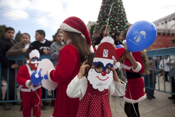 Niños palestinos vestidos con trajes de Santa Claus se reúnen fuera de la Iglesia de la Natividad, en Belén, Cisjordania.