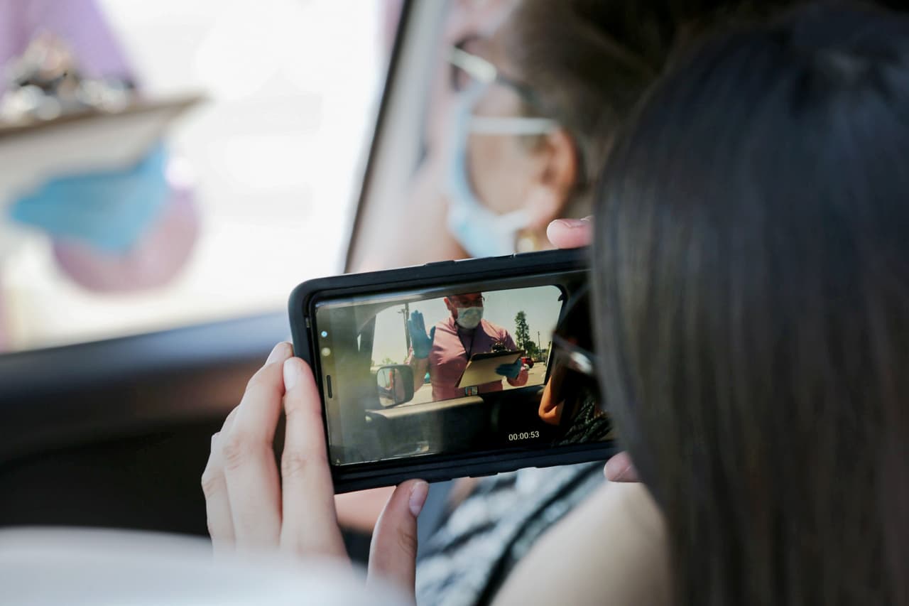 La acompañante de un nuevo ciudadano graba con su teléfono el juramento en una ceremonia de naturalización desde el auto en Santa Ana, el último paso del proceso de ciudadanía. 29 de junio.