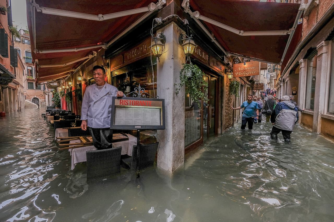 El dueño de un restaurante mira las aguas entrar a su local en Venecia. La marea alcanzó más de 5 pies (156 centímetros) sobre el nivel regular.