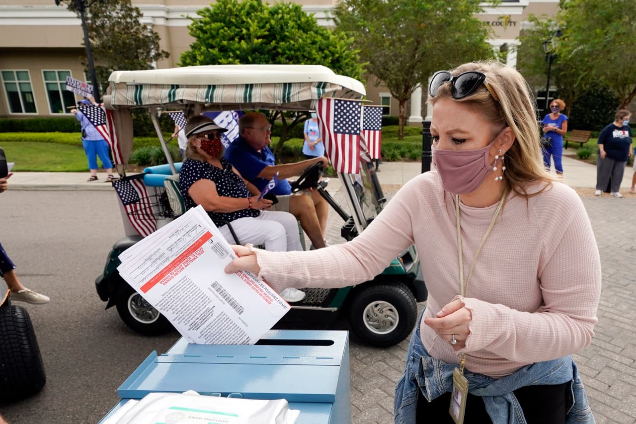 Una empleada del departamento de elecciones deposita la boleta de una votante en una caja de recolección de sufragios en el condado de Sumter, Florida, el 7 de octubre. A semanas del día de las elecciones, millones de estadounidenses han utilizado las alternativas de votación temprana de sus estados.