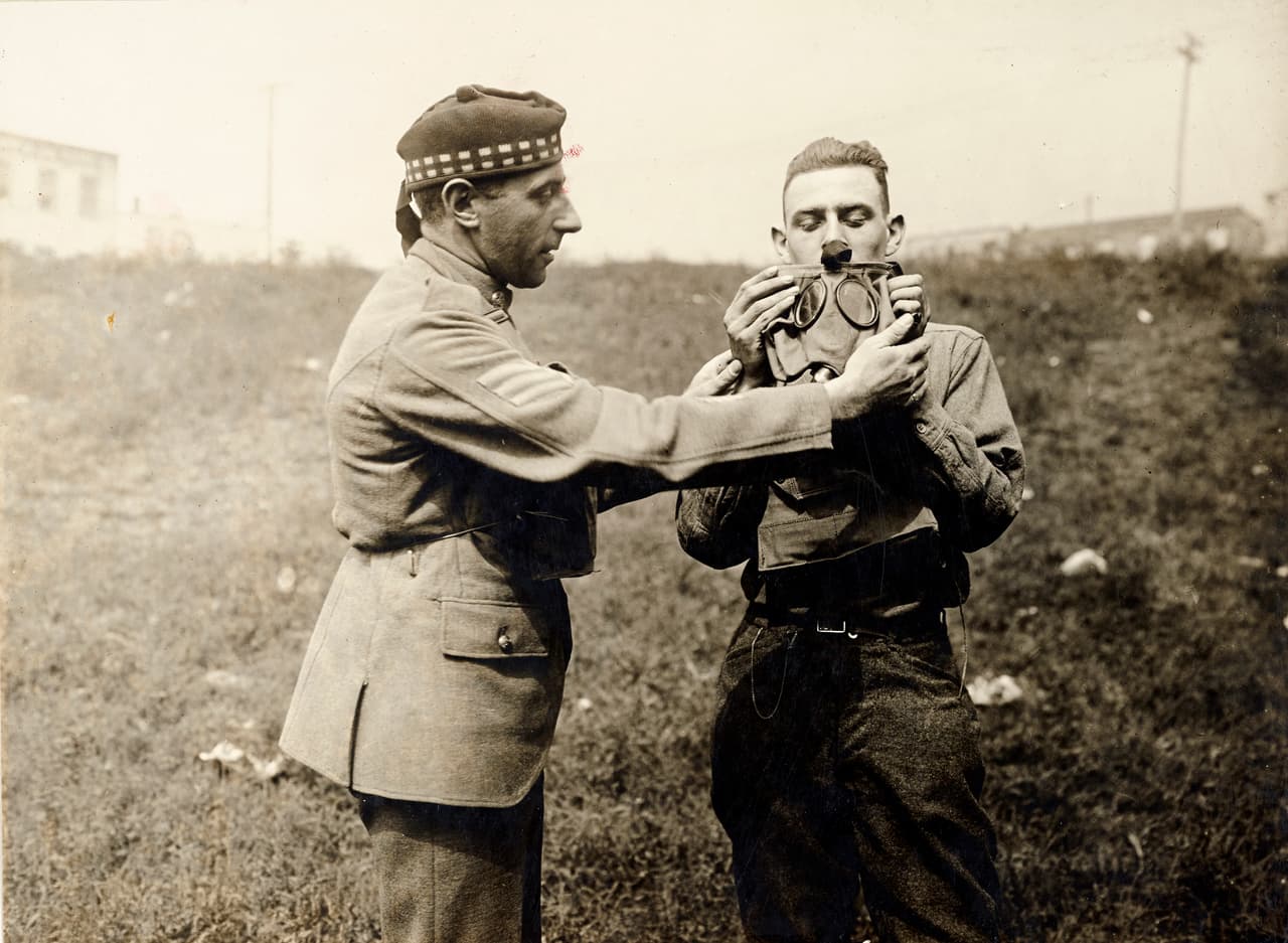 <b>Entrenamiento Aliado.</b> Un sargento escocés dando instrucciones sobre cómo ajustar máscaras de gas a un soldado estadounidense. Aunque la intención del presidente Wilson era mantener a EEUU fuera de la guerra, la inminente posibilidad de un nuevo conflicto con México metió a EEUU de lleno en la guerra.