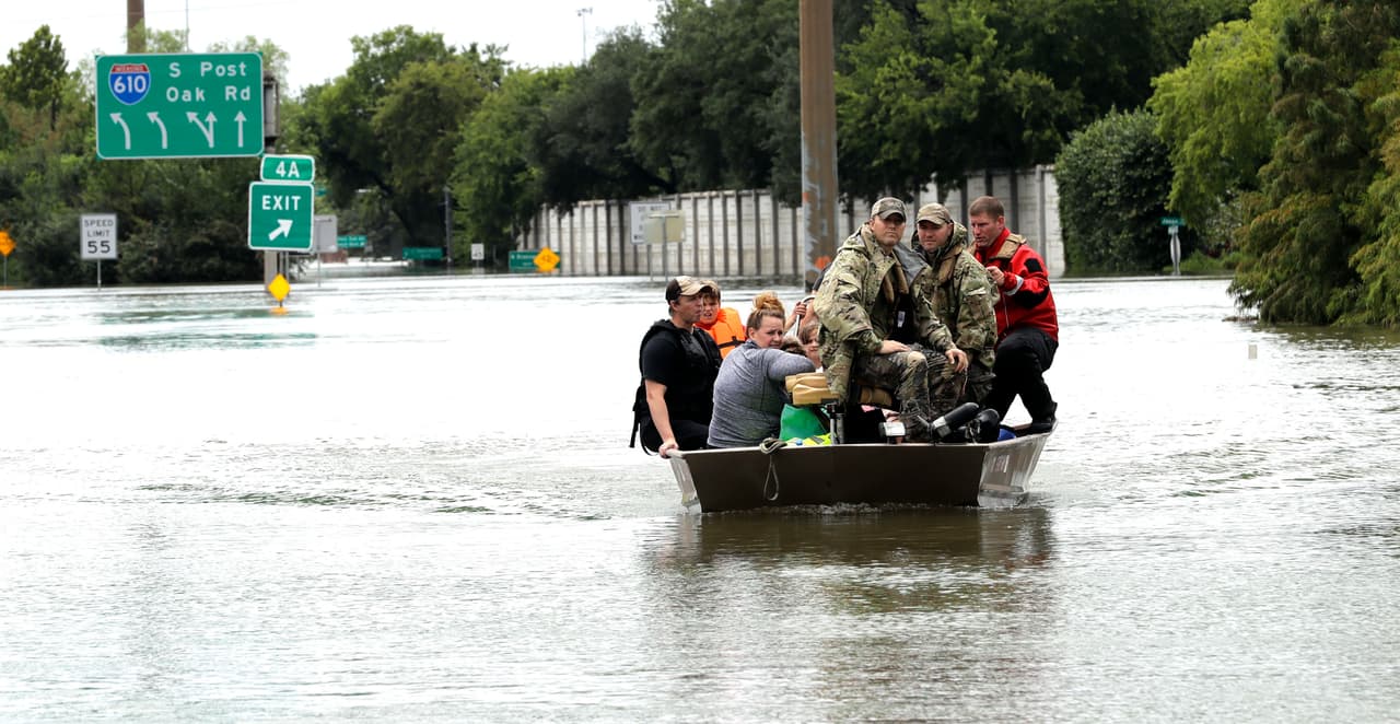 Residents float down a flooded Houston street. Donald Trump will travel to the state Tuesday to examine the damage.
