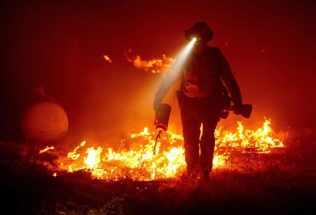 Los bomberos cortaron las líneas defensivas y encienden contrafuegos para proteger las estructuras detrás de una estación de bomberos de CalFire durante el incendio de Bear, parte de los incendios del North Lightning Complex en el área de Berry Creek del condado no incorporado de Butte, California, el 9 de septiembre de 2020.