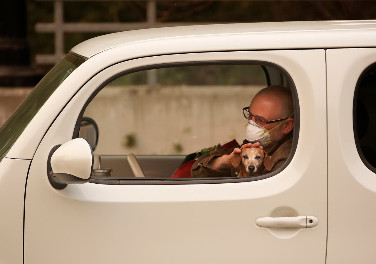 Chris Shiery acaricia a su perro, Ruby, mientras espera evacuar el condado de Sonoma, uno de los más afectados.