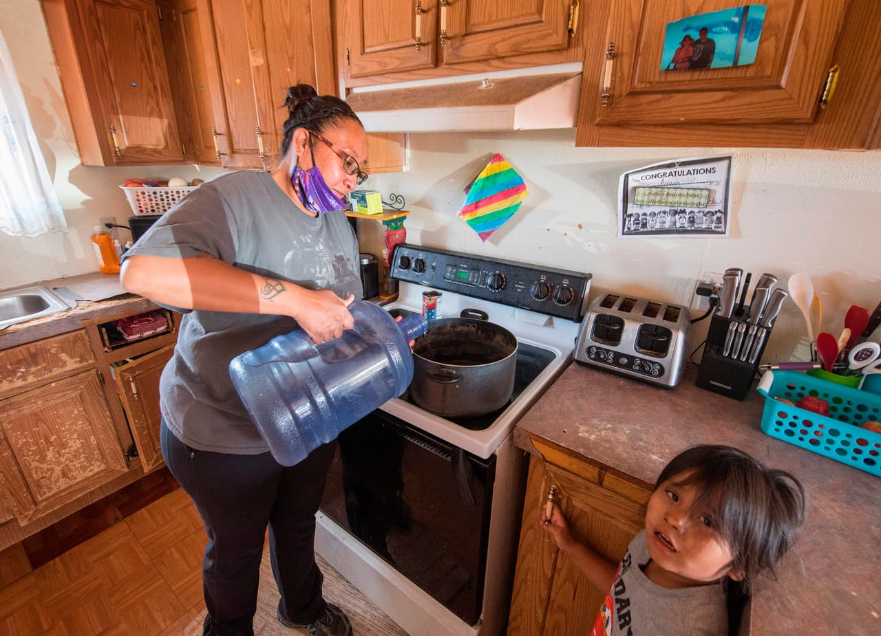 Amanda Larson, que no tiene agua corriente en su casa, lleva agua para que su hijo Gary Jr se bañe en la ciudad de Thoreau, Nación Navajo, afectada por el Covid-19, en New México.