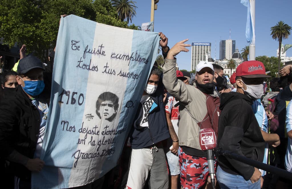 Un grupo de fanáticos de 'El Pelusa' asisten a su funeral en la Casa Rosada en Buenos Aires. Miles de personas se dieron cita en las calles de la capital argentina para despedir al ídolo del futbol sin respetar la distancia social y muchos sin llevar mascarilla pese a los peligros por covid-19.