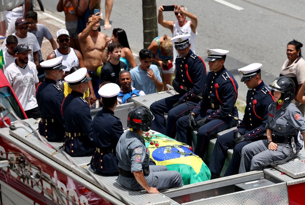 El ataúd cubierto con la bandera brasileña de la leyenda del fútbol Pelé es transportado encima de un camión de bomberos en una procesión fúnebre por las calles de Santos camino a su lugar de descanso final en el cementerio Memorial Necrópole Ecumênica el 03 de enero de 2023 en Santos, Brasil.