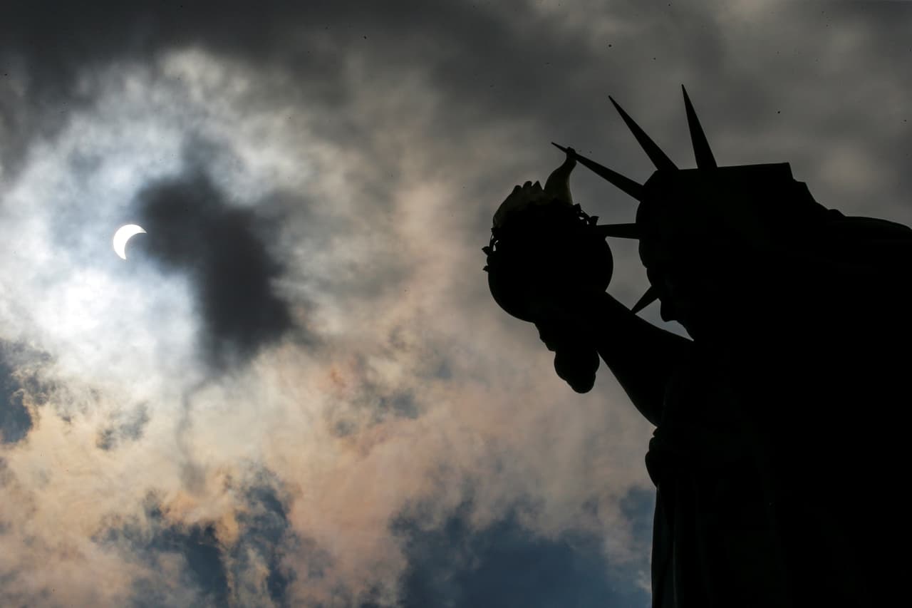 El sol a medio tapar desde la Estatua de la Libertad. (Eduardo Muños/Reuters)