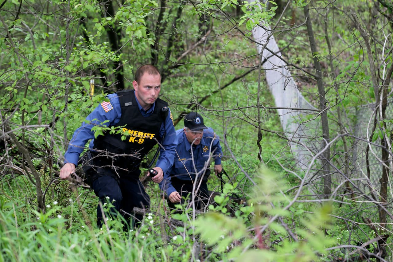 Una unidad canina de la policía examina la zona adyacente a la vía donde ocurrió el accidente.