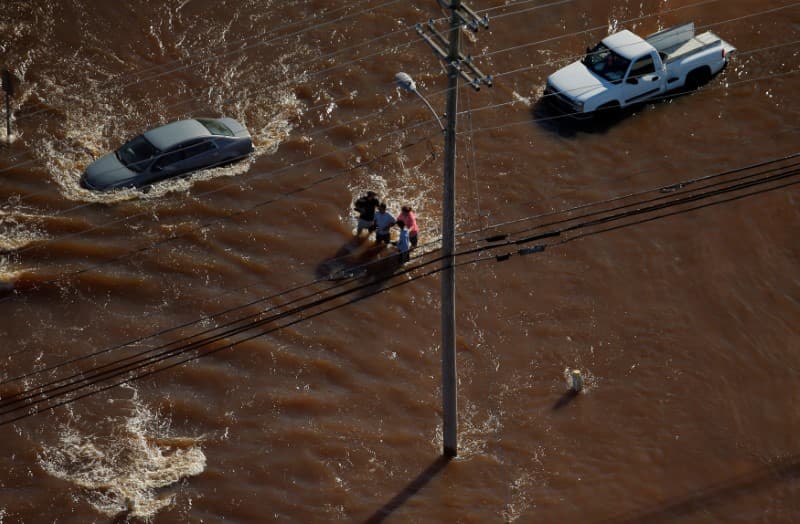 Residentes caminan agarrados por una calle inundada. Cerca de 4,000 personas permanecían refugiadas, más de 1,000 en Lumberton. (REUTERS/Chris Keane)
