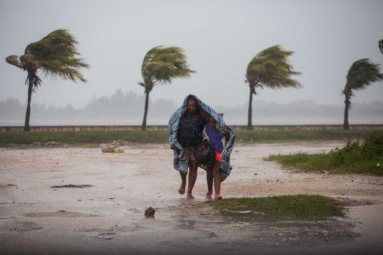 Una mujer y un niño bajo una manta se protegen contra el viento y la lluvia mientras caminan en Caibarien, Cuba. El huracán Irma golpeó a Cuba el sábado con vientos y lluvia incesante. Se han reportado marejadas e inundaciones hacia el interior de la isla.
