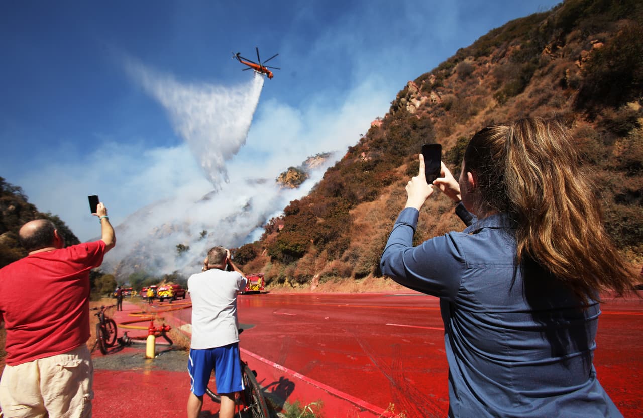 Gente se detuvo en la zona para tomar fotos con sus teléfonos celulares de la operación desplegada por los bomberos. La vía fue cubierta con una capa de material antiinflamable que rociaron desde aviones.