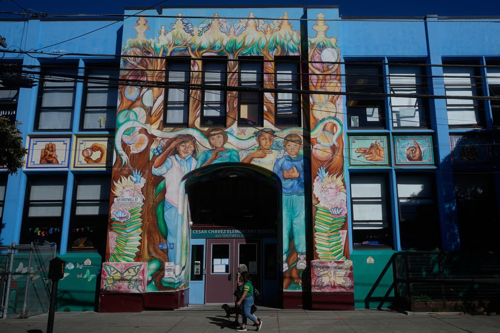 Unos peatones pasan junto a un mural situado en el exterior de la escuela primaria César Chávez, en San Francisco, el miércoles 18 de marzo de 2026.