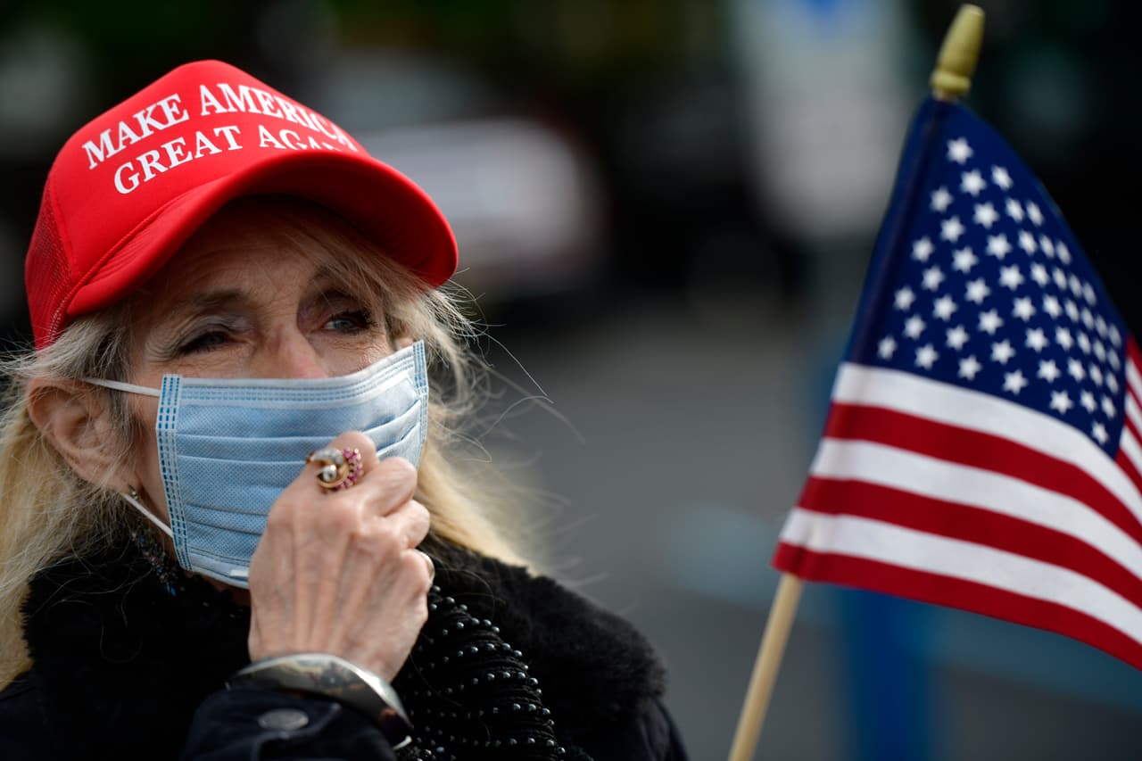 Una manifestante con el sombrero "Hacer a Estados Unidos grande de nuevo", lema del campaña del presidente Donald Trump, ajusta su mascarilla mientras se reúne afuera del gimnasio Atilis el 20 de mayo.