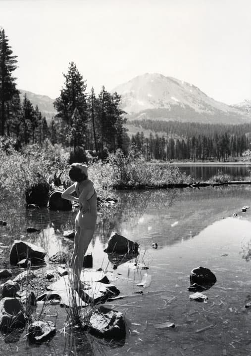 Una mujer en traje de baño se posa sobre unas rocas en el lago Manzanita en California, en 1934. Al fondo se observa el Monte Lassen del Parque Nacional Volcánico Lassen.