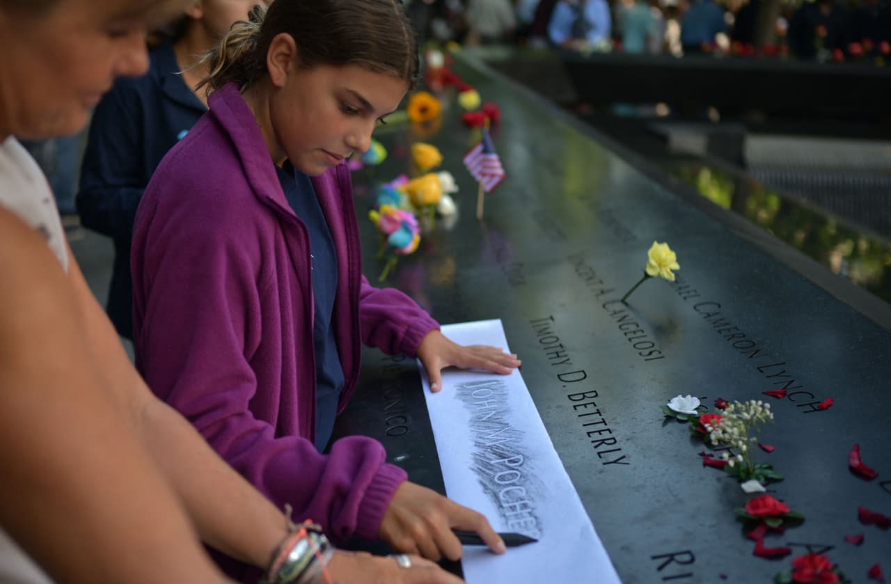 Una de las tradiciones más comunes en esta ceremonia es calcar los nombres de los familiares que murieron, como esta niña está haciendo en la foto.