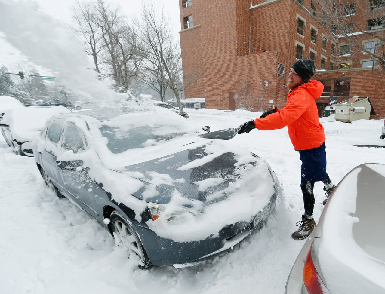 John Malsbary lanza una pala de nieve por encima de su coche mientras trata de sacarlo de donde se encuentra estacionado y rodeado de nieve.