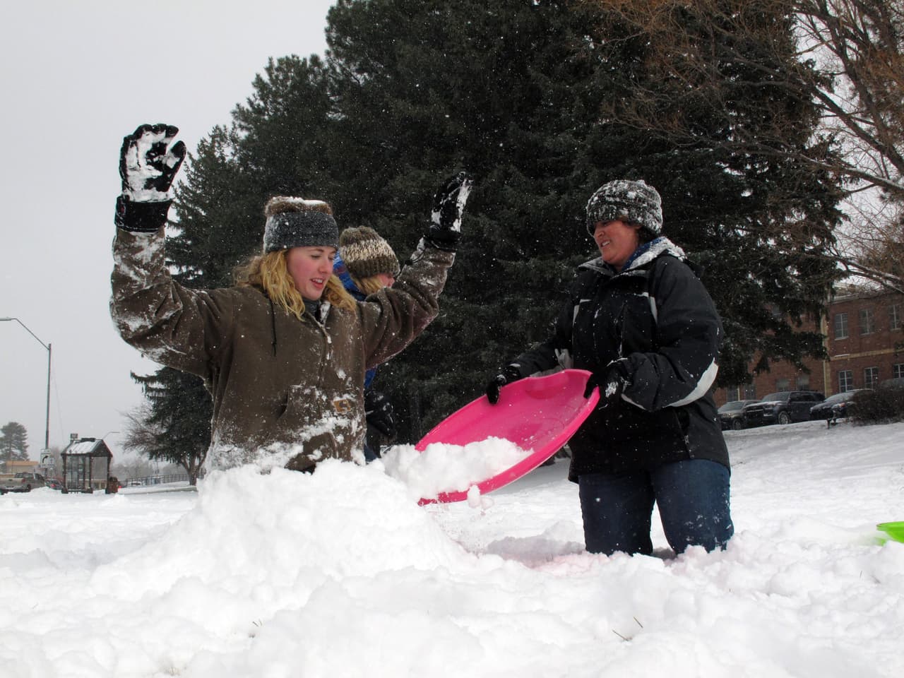 Kaitlyn Ayala y su amiga Emily Romine tratan de remover la nieve que quedó en Flagstaff, Arizona.