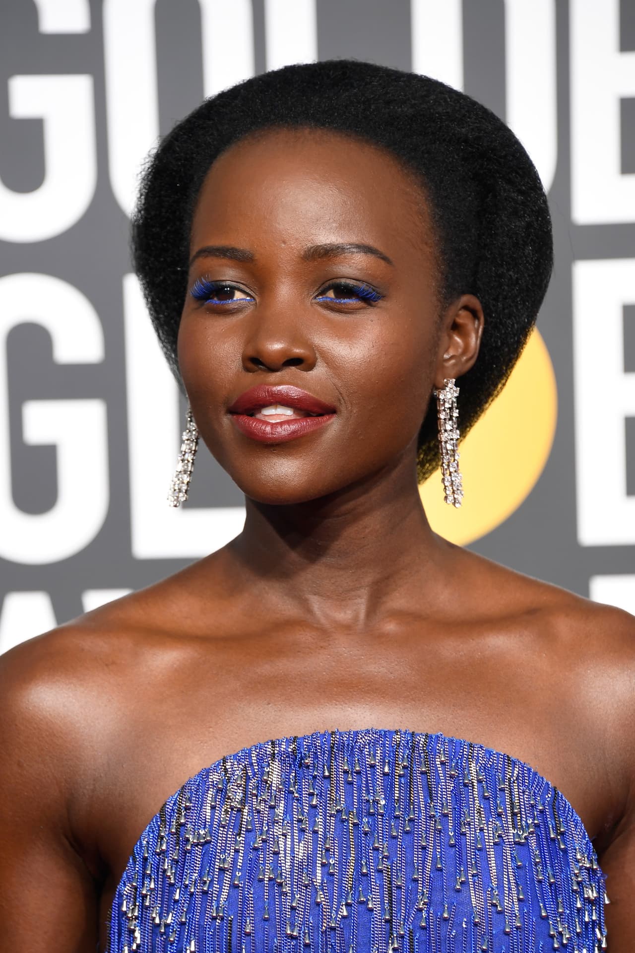 Lupita Nyong'o desfiló con un vestido azul metálico de Calvin Klein, además de arriesgarse en pintar sus pestañas del mismo color, sin sombras en los ojos para neutralizar.