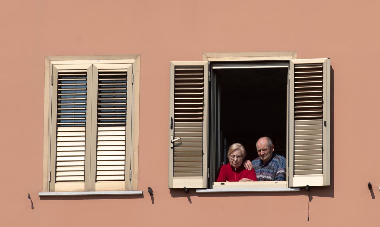Una pareja observa una misa por el "Domingo de Ramos' desde su ventana en Roma, Italia.
