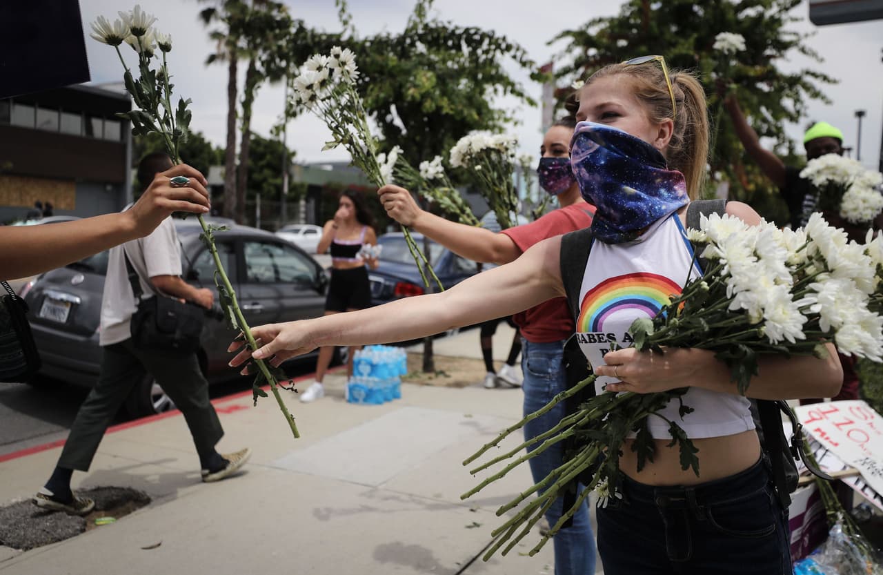 A cinco meses de las elecciones presidenciales, el presidente Trump sumó crispación tras amenazar el lunes con movilizar al ejército para imponer el orden, después de que al margen de las protestas en varias ciudades se registraran disturbios con saqueos. Sin embargo, la mayor parte de los manifestantes salieron a las calles de forma pacífica, como esta joven, algunos repartieron flores a los que iban llegando a la manifestación en Los Ángeles.
<b> </b>