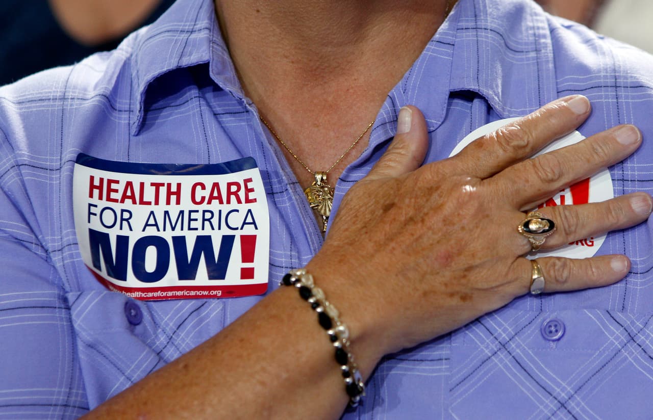 Una miembro de la audiencia toma el juramento de lealtad antes de la llegada de Obama a un 
<i>town hall</i> sobre la reforma de seguros de salud en la secundaria Portsmouth, New Hampshire, en 2009. De acuerdo a una encuesta de The Associated Press y del Centro NORC para Investigaciones de Asuntos Públicos realizada en enero de 2017, 
<b>56% de los adultos estadounidenses está "extremadamente" o "muy" preocupado</b> 
<b>de que muchos pierdan sus seguros médicos</b>, si la ley llega a ser revocada.