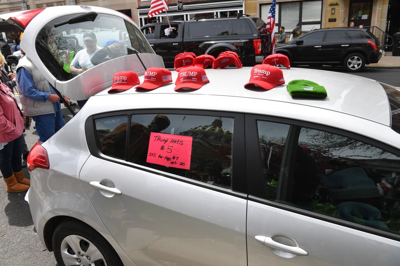 Los sombreros del presidente de Estados Unidos, Donald Trump, se ven a la venta mientras las personas participan en una manifestación de "reapertura" en Pensilvania el 20 de abril de 2020 en Harrisburg, Pensilvania.