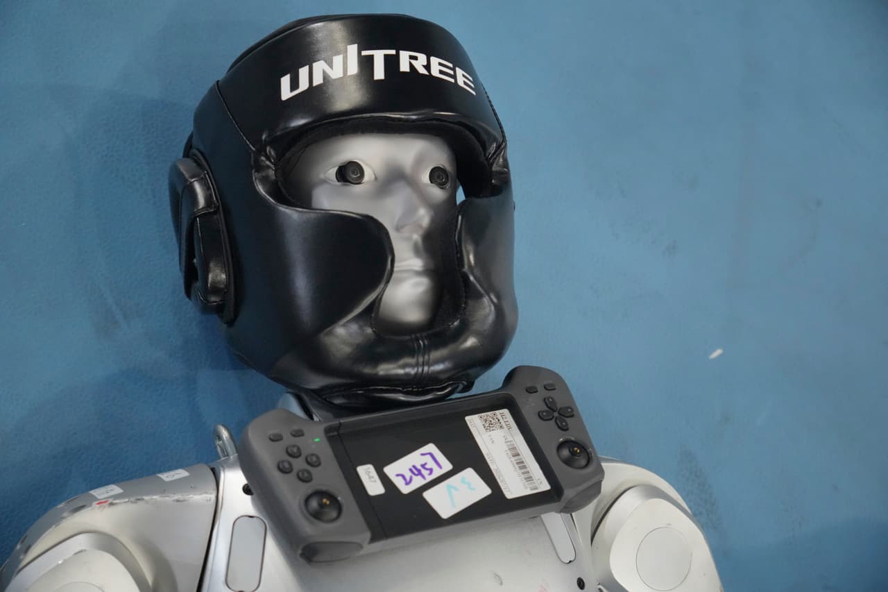 Un robot humanoide yace en el suelo con su control remoto antes de competir en el combate libre.