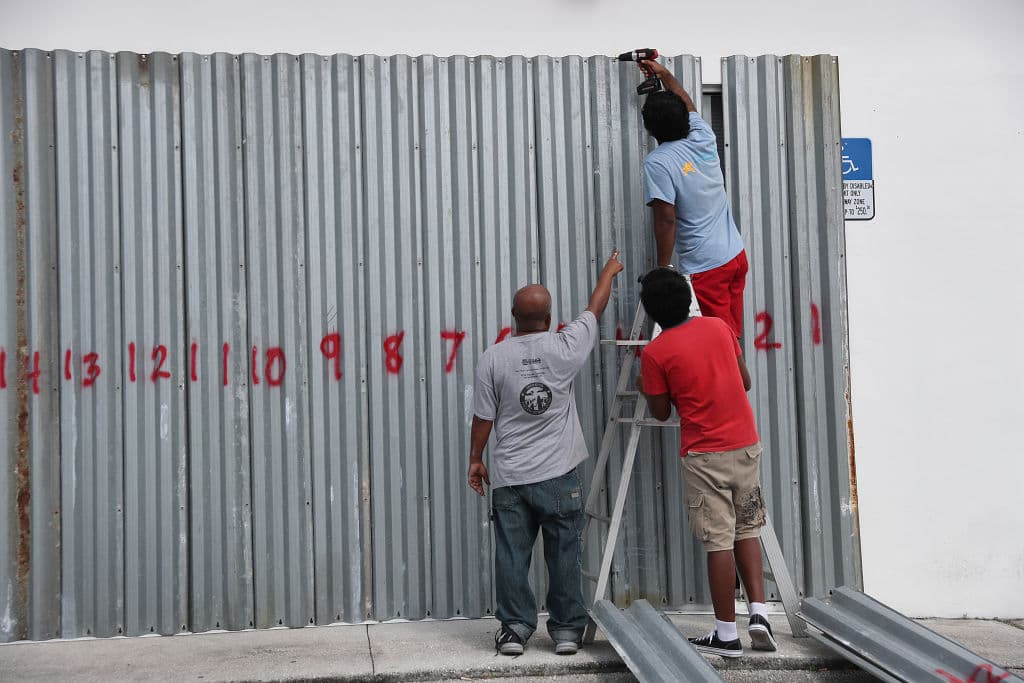 Trabajadores colocan paneles antihuracanes (shutters) sobre las ventanas de un Food Mart este domingo en Riviera Beach, Florida. 
<br>
<br>